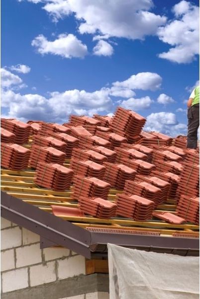 Roof tiles stacked up on a wooden roof frame, ready to be secured in place.
